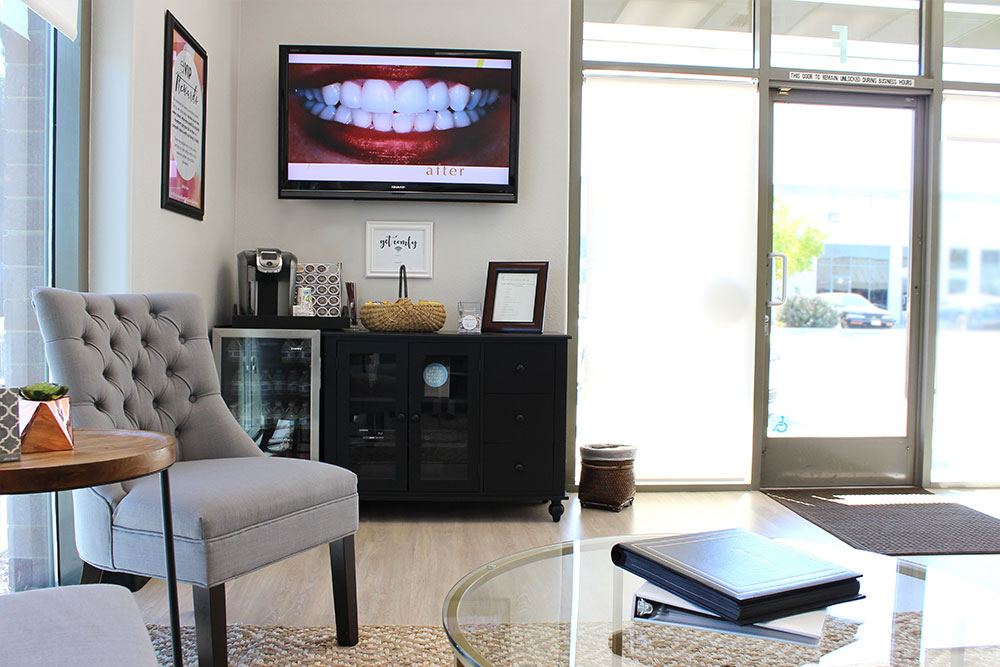 exceptional dentistry waiting room with a tv, desk, table, and a couch