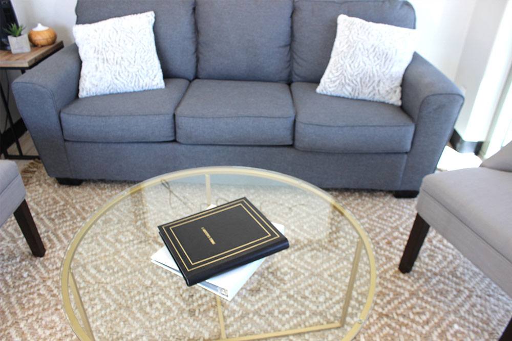 a table with a book on it, with a couch behind