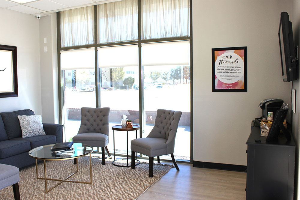 exceptional dentistry waiting room with couches, a tv, and tables